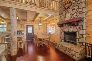 Ein Holzblockhaus-Interieur mit Kamin aus Stein, einem Holzespeisesaal und Stühlen.