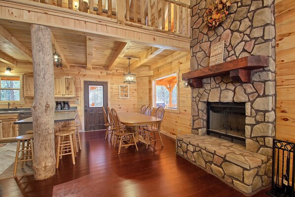 L’intérieur d’un chalet en bois, avec une cheminée en pierre, une table à manger en bois et des chaises.