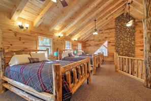 Ein Blockhauszimmer mit zwei Betten, einer Steinwand und einer Holzbalkendecke.
