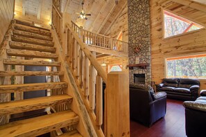 Un escalier en bois, un mur en pierre et une cheminée dans un intérieur de style chalet.