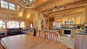 A spacious wooden cabin interior with a dining area, kitchen, and living room. - Dogwood Lane Lodge- sleeps up to 18 -Hocking Hills (Logan)