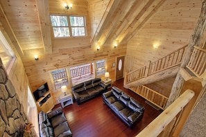 A spacious wooden interior with a high ceiling, a stone wall, and a cozy seating area with leather sofas. - Dogwood Lane Lodge- sleeps up to 18 -Hocking Hills (Logan)