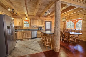 L’intérieur d’un chalet en bois comprend une cuisine, un coin repas et de grandes fenêtres.