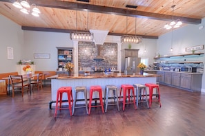 A modern kitchen with a central island, bar stools, and a stone backsplash.