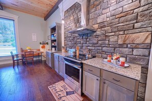 A modern kitchen with a stone wall backsplash, wooden flooring, and a built-in oven. - Chapel Valley Lodge - Unique, in the Hocking Hills (Logan)