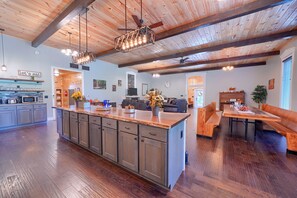 A spacious kitchen with a central island, wooden ceiling beams, and a dining area with a bench. - Chapel Valley Lodge - Unique, in the Hocking Hills (Logan)