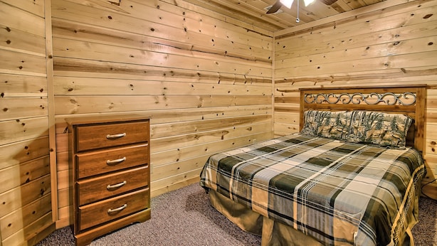 A bedroom with a wooden headboard, a bed with a plaid bedspread, a wooden dresser with drawers, and a ceiling fan. - Double Pine Lodge - 5 Bedroom -Hocking Hills (Logan)