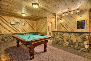 Ein Billardtisch in einem Raum mit Holzwänden und einer Wand aus Stein.