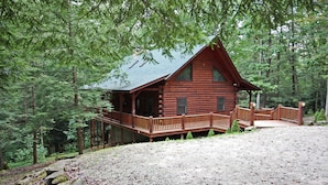 A log cabin with a porch and a covered deck, surrounded by a forest. - Double Pine Lodge - 5 Bedroom -Hocking Hills (Logan)