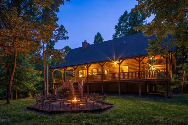 A wooden cabin with a deck, outdoor seating, and a fire pit.
