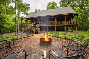 A lodge with a fire pit, outdoor seating, and a covered deck.