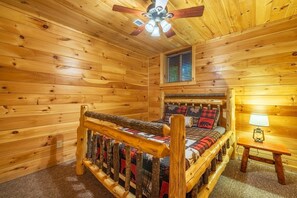 A log cabin bedroom with a wooden bed, a ceiling fan, a window with blinds, and a nightstand with a lamp. - Timber Ridge Lodge - 5-BR, w/King Suite - Hocking (Logan)