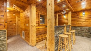 Un intérieur en bois agrémenté d’un mur en pierre, de colonnes en bois et d’un espace bar avec des tabourets.