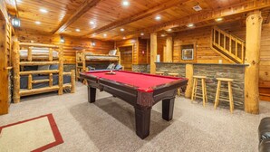 Un intérieur en bois avec une table de billard, des lits superposés et un escalier.