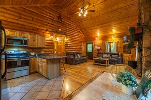 A log cabin interior with a kitchen, dining area, and living room. - Hunter's Retreat - Cozy Cabin, near Old Man's Cave (Logan)