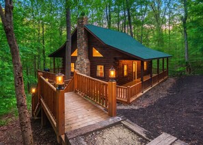A wooden cabin with a stone chimney, wooden deck, and a covered porch. - Hunter's Retreat - Cozy Cabin, near Old Man's Cave (Logan)