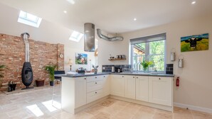 A modern kitchen with a large island, a brick wall, and a skylight. - 4 bedroom accommodation in Wimborne (Wimborne)