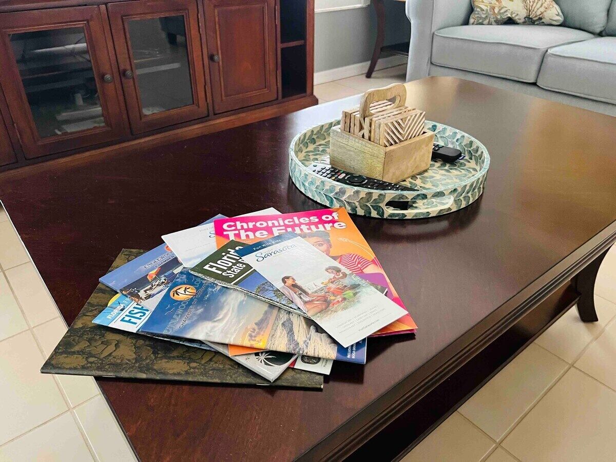 A dining table with magazines and a tray of wooden utensils.