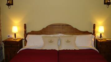 Ein Doppelbett mit Holz-Kopfteil, zwei Nachttische mit Lampen sowie dekorative Wandleuchten.