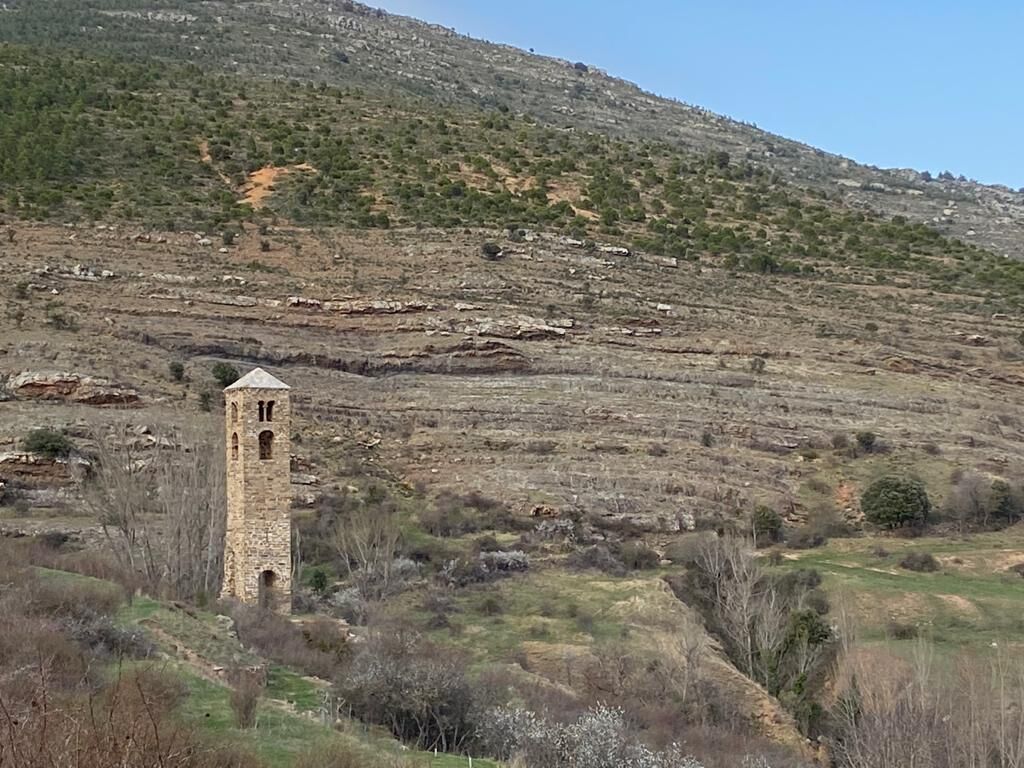 A stone tower in a hilly landscape with sparse vegetation.
