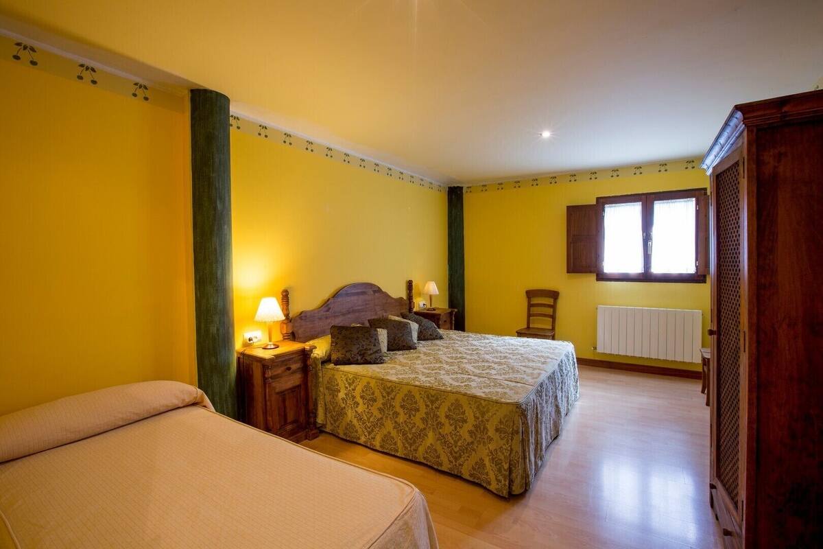 A bedroom with a bed, bedside tables, a chair, a window, and a radiator.