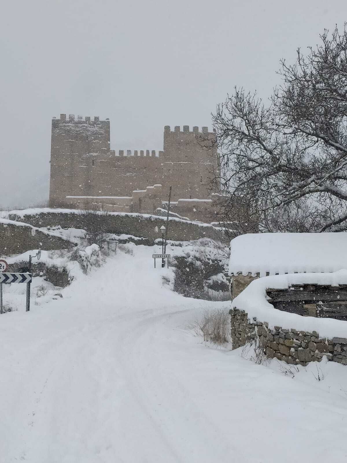 Une route enneigée menant à un château de pierre historique.