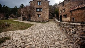 Ein steinbelagter Weg führt zu traditionellen Steinhäusern mit rustikalem, historischem Aussehen.