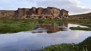 A house with a flat roof and a large rock formation in the background.