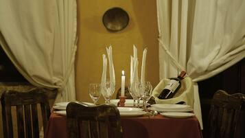 Una mesa de comedor dispuesta con platos blancos, copas de vino y una vela.
