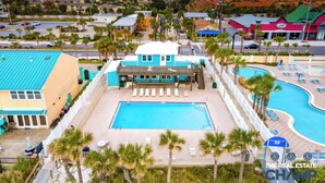 Un resort con una piscina grande, un edificio de techo azul y palmeras.
