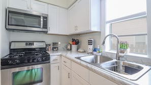 Una cocina moderna con electrodomésticos de acero inoxidable, armarios blancos y un amplio ventanal que proporciona luz natural.