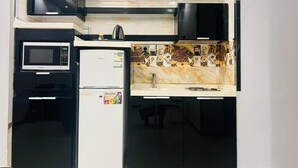 Une cuisine compacte équipée d’un four à micro-ondes, d’un réfrigérateur et d’une machine à café.