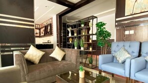 Un salon moderne avec un canapé marron, un fauteuil bleu et une table basse en verre.