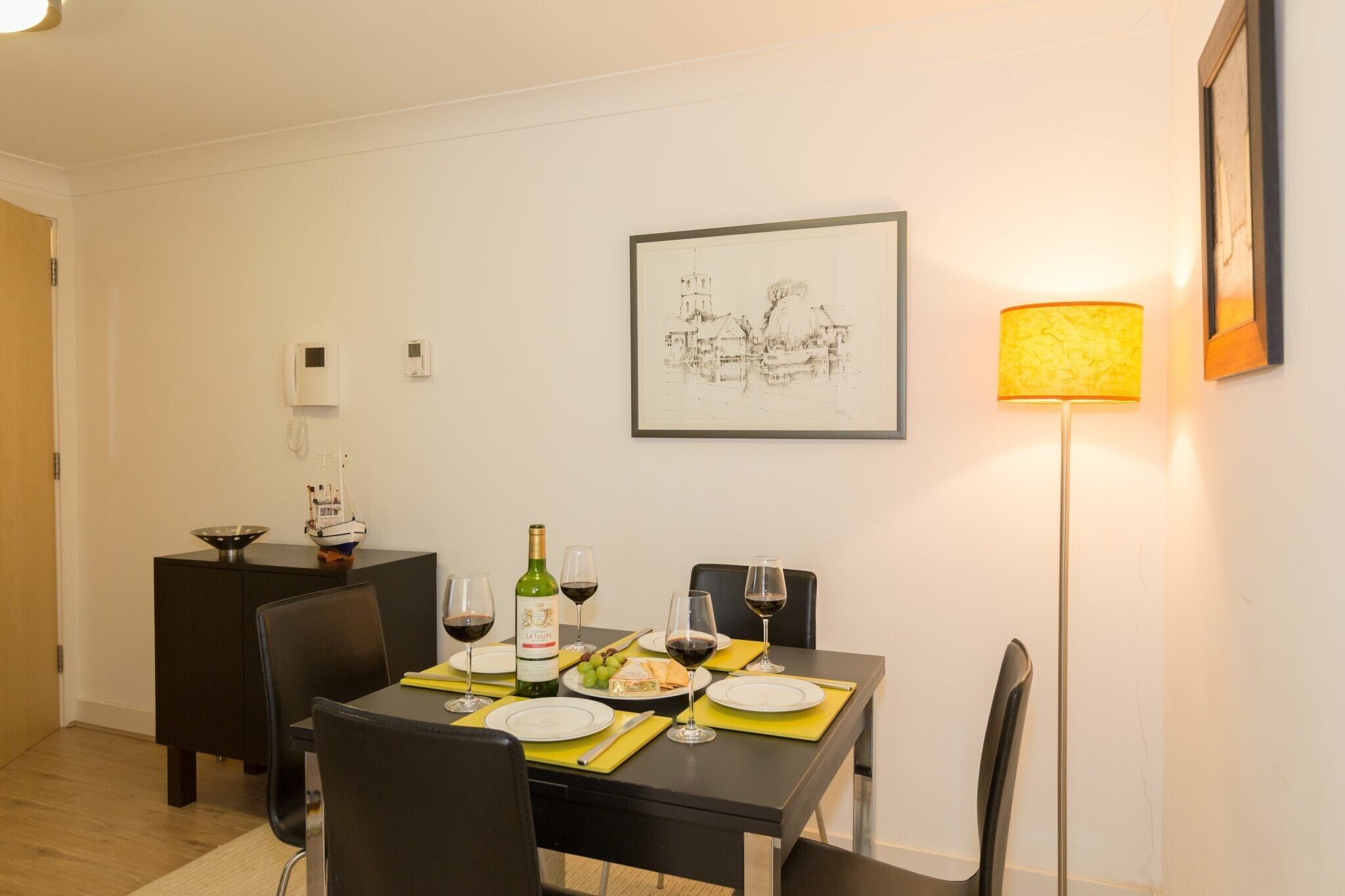 Ein Essbereich mit einem Tisch für zwei Personen, komplett mit einer Weinflasche, Gläsern, Tellern mit Essen und einer Lampe.