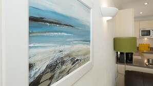 A modern kitchen with a large abstract painting on the wall, a green lamp, and a microwave. - The Point (St Ives)
