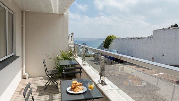 A balcony with a table set for breakfast, overlooking a coastal view. - The Point (St Ives)