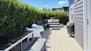An outdoor deck with a sofa, chairs, and a table. - Treasure on Tuscan - Martinborough Holiday Home (Martinborough)