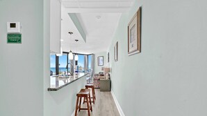 A narrow hallway with a kitchen area featuring a sink, stools, and a view of the ocean. - ⭐Newly Renovated, Beachfront-1BR Sunbird 309E⭐ (Panama City Beach)