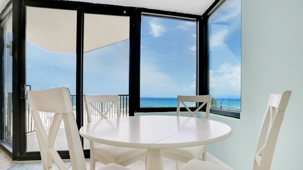 A round white table with four chairs in a room with large glass doors leading to a balcony with a view of the ocean. - ⭐Newly Renovated, Beachfront-1BR Sunbird 309E⭐ (Panama City Beach)