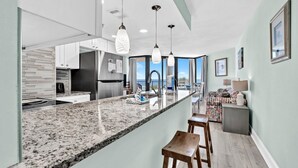 A modern kitchen with granite countertops, stainless steel appliances, and pendant lighting. - ⭐Newly Renovated, Beachfront-1BR Sunbird 309E⭐ (Panama City Beach)