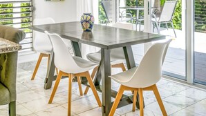 A modern dining area with a large table, white chairs, and a vase.