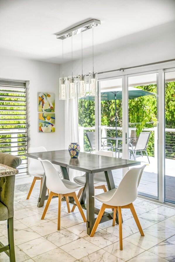 A modern dining area with a large table, white chairs, and a vase.