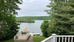 Une terrasse dotée de mobilier d’extérieur, offrant une vue sur un lac et entourée d’arbres.
