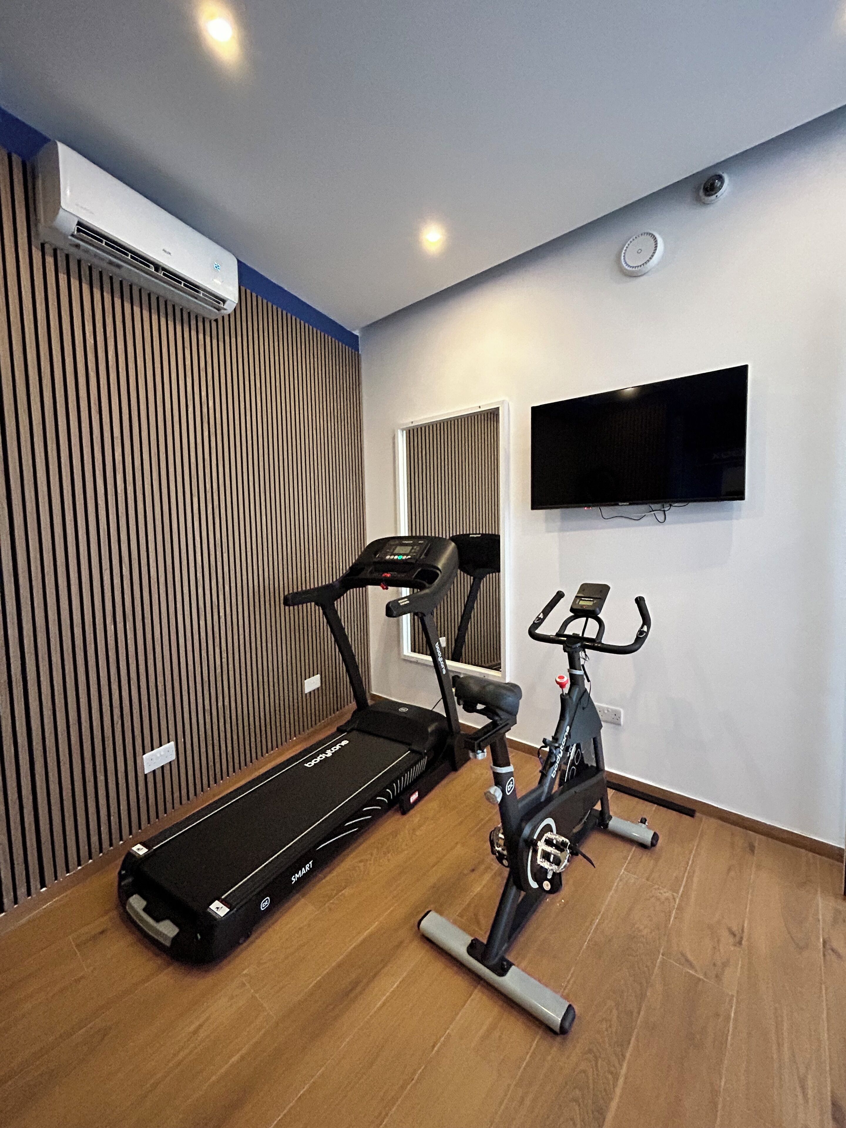 A modern gym with a treadmill, an elliptical, and a stationary bike.