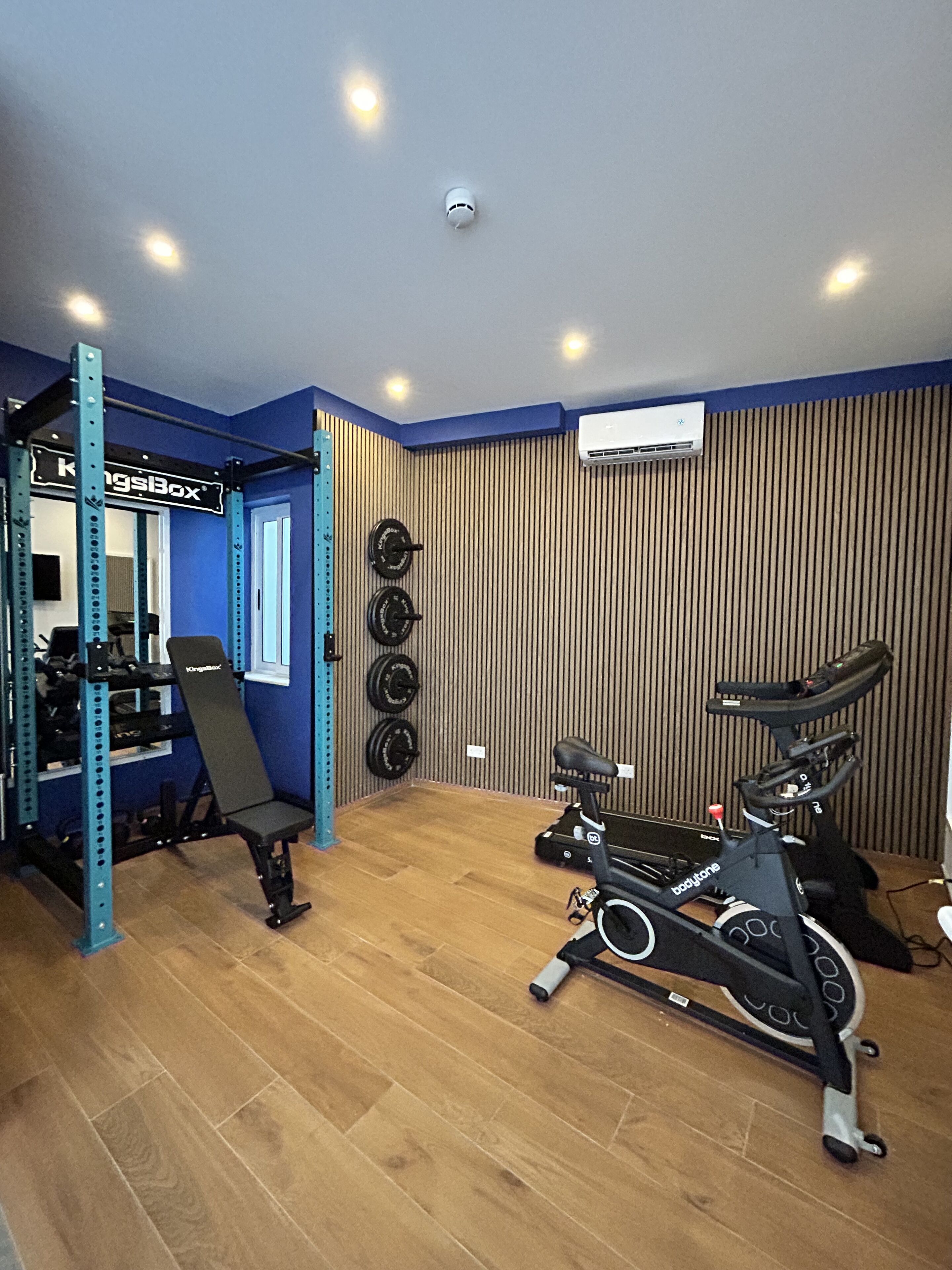 Een sportschool thuis met een optrekstang, een bank en een hometrainer.