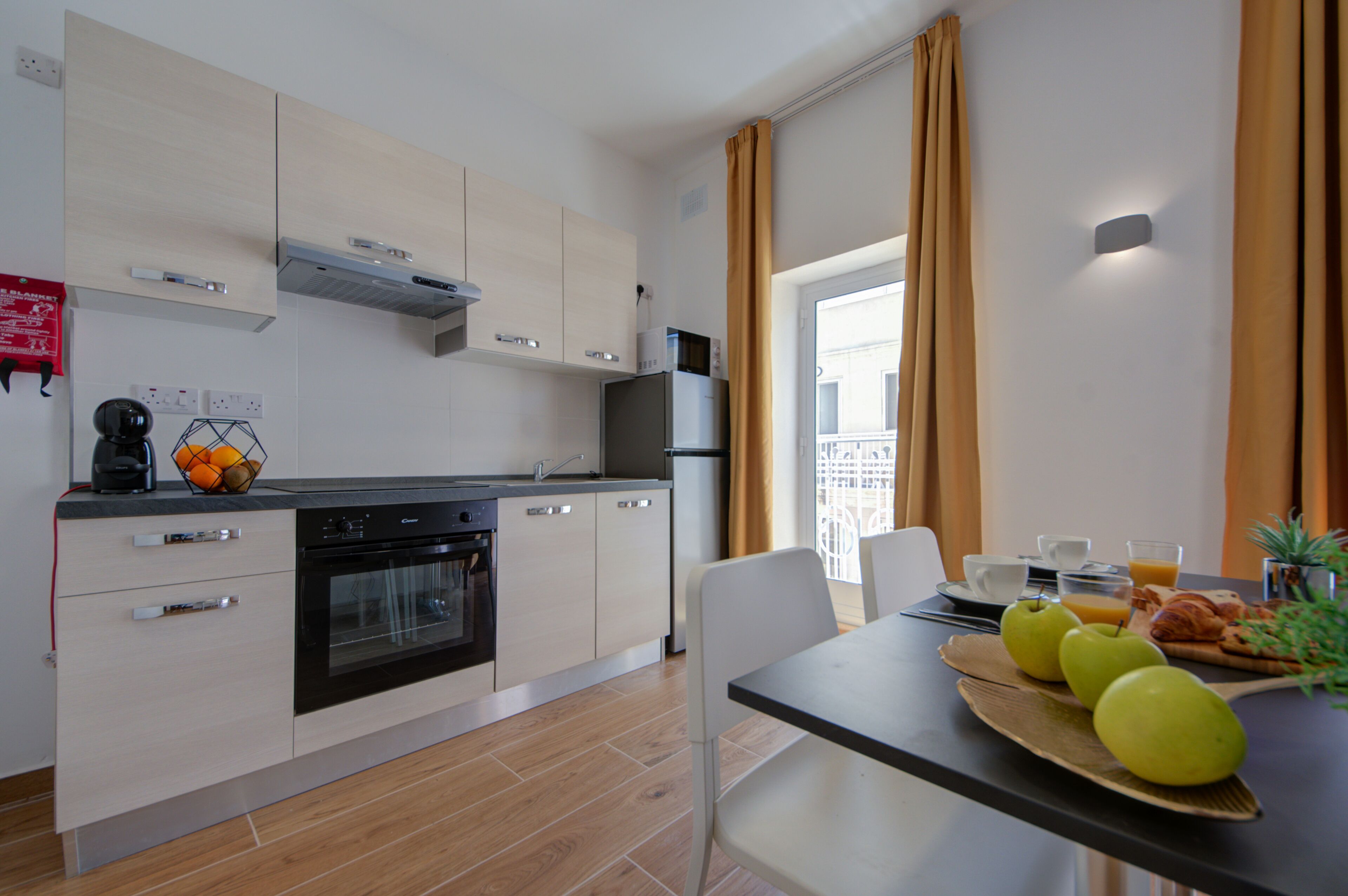 Una cucina moderna con mobili bianchi, un forno nero e un'area pranzo con la tavola apparecchiata per la colazione.