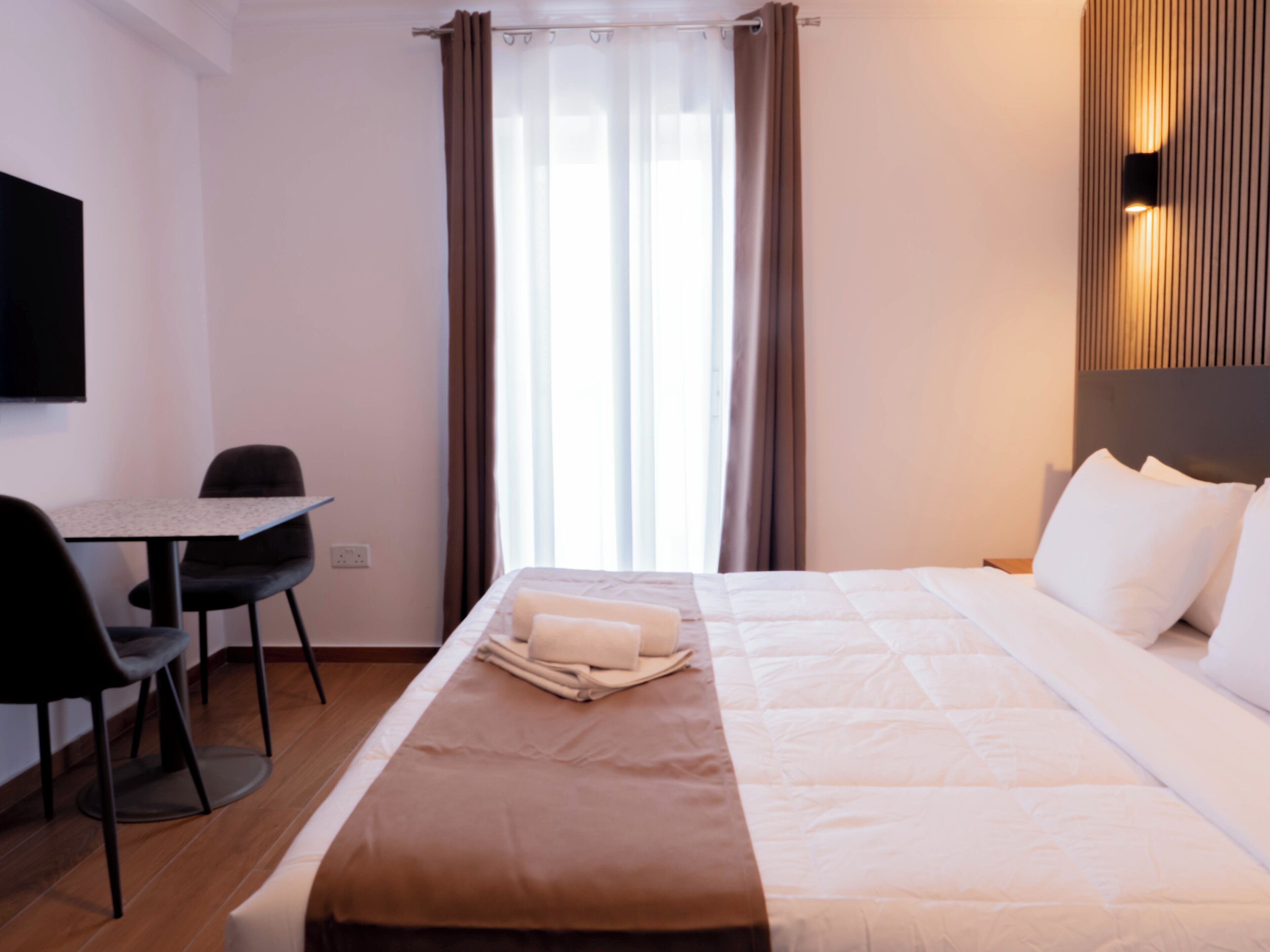 Habitación de hotel con cama, escritorio, silla y televisión.
