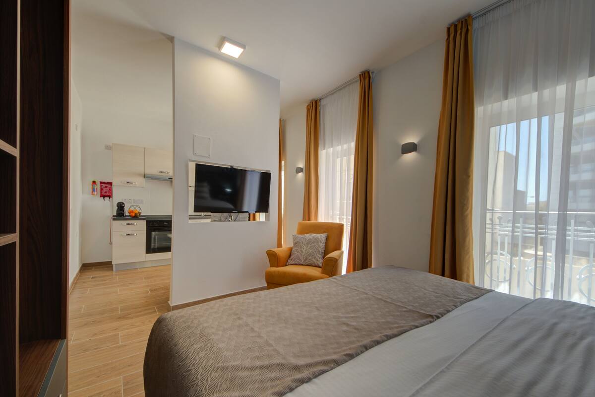 Ein Hotelzimmer mit Bett, Fernseher, Sessel und Blick ins Freie.