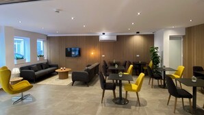 Un espace de détente moderne offrant différents types de sièges, notamment des canapés et des fauteuils, un téléviseur à écran plat fixé au mur et un plafond en bois doté d’un éclairage encastré.
