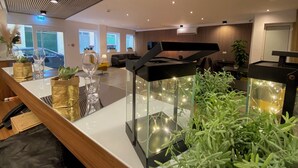 Un hall d’hôtel moderne avec une table basse en verre, des plantes en pot et un piano.